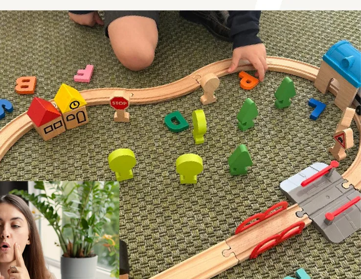Infants jugant amb un circuit de tren de fusta sobre una catifa